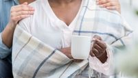 woman wearing shawl and holding cup of coffee with someone's hands on her shoulders