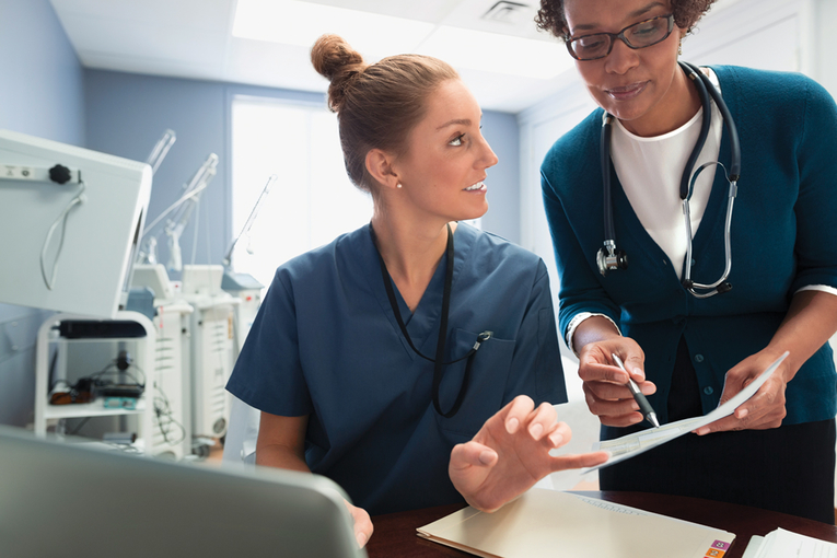 Nurse talking to a doctor while using a computer.